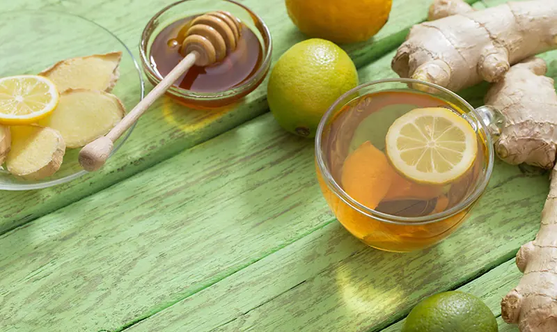 Tasse Tee mit Honig und Zitronenscheibe zeigt gesunde Verwendung