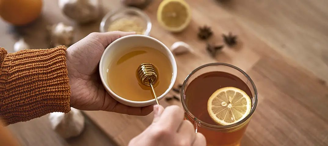 Honig tropft von Löffel zur natürlichen Behandlung von Halsschmerzen